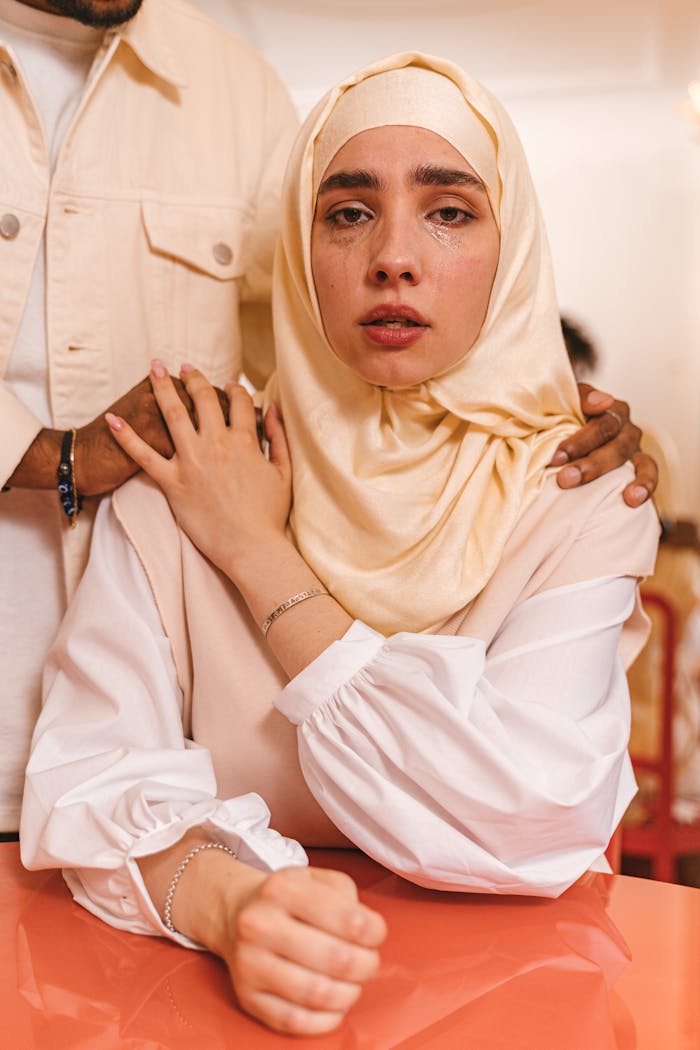 A woman in a hijab receives comfort from a supportive companion in an emotional moment.